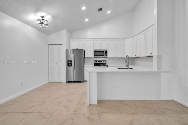 kitchen featuring appliances with stainless steel finishes, light tile patterned floors, a textured ceiling, white cabinets, and sink