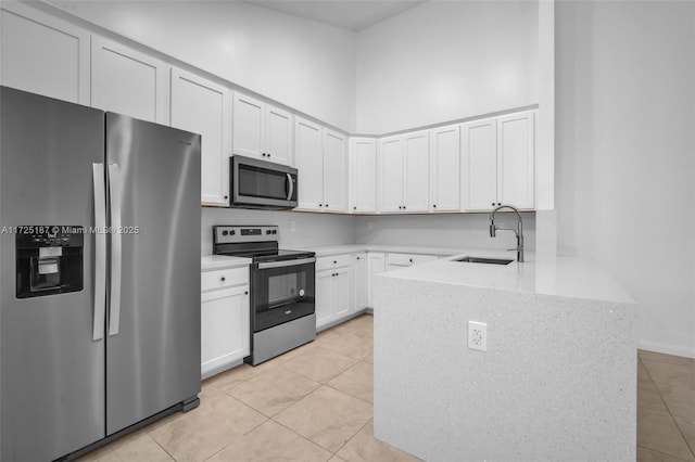 kitchen with stainless steel appliances, sink, white cabinetry, light stone counters, and light tile patterned floors