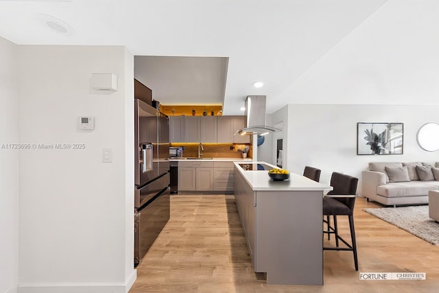 kitchen featuring a breakfast bar, island exhaust hood, a kitchen island, high end refrigerator, and sink