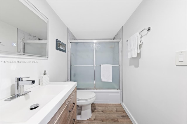 full bathroom featuring toilet, shower / bath combination with glass door, vanity, and hardwood / wood-style floors