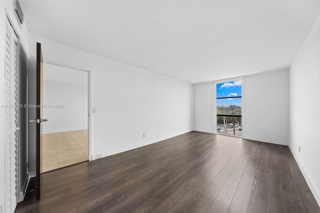 spare room with a wall of windows and dark wood-type flooring