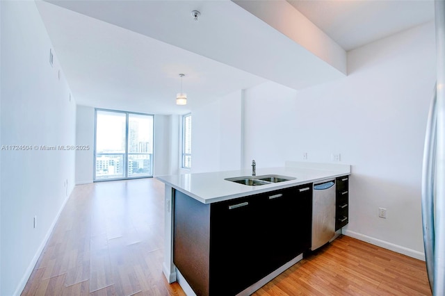 kitchen featuring dishwasher, hanging light fixtures, light hardwood / wood-style floors, expansive windows, and sink