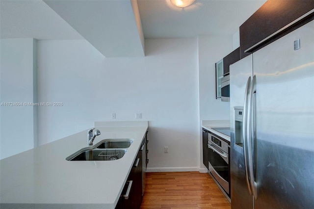 kitchen featuring appliances with stainless steel finishes, light hardwood / wood-style flooring, and sink