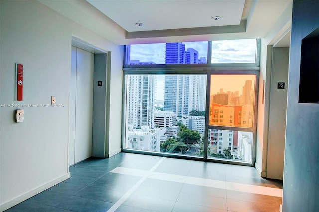 unfurnished room with tile patterned floors, elevator, and expansive windows