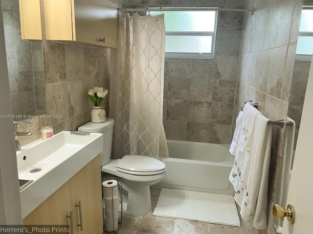 full bathroom featuring toilet, shower / tub combo, vanity, and tile walls