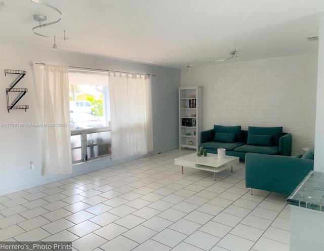 living room featuring brick wall, rail lighting, ceiling fan, and light tile patterned floors