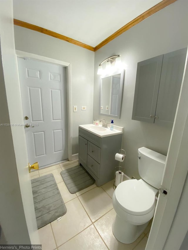 bathroom with toilet, tile patterned flooring, ornamental molding, and vanity