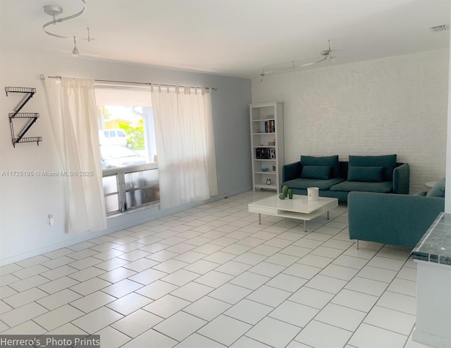 living room featuring ceiling fan, light tile patterned flooring, brick wall, and rail lighting