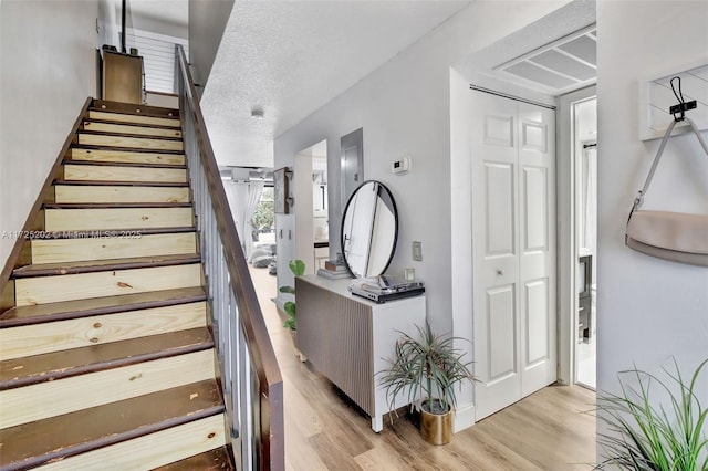 stairway featuring a textured ceiling and wood-type flooring