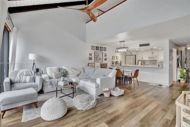 living room with high vaulted ceiling, light wood-type flooring, and beamed ceiling