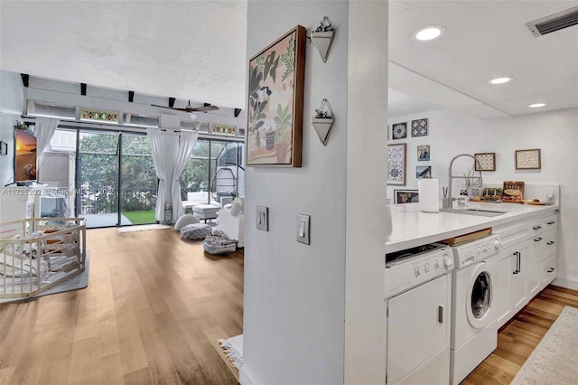 laundry area featuring sink, light wood-type flooring, and independent washer and dryer