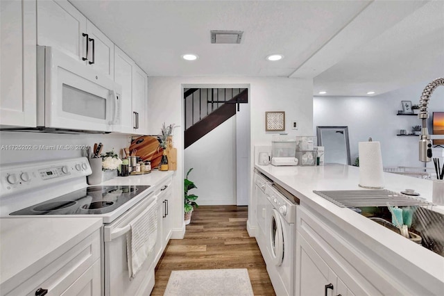 kitchen with white appliances, white cabinetry, washer and clothes dryer, and wood-type flooring