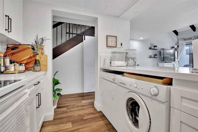 laundry room with washing machine and dryer and light hardwood / wood-style floors