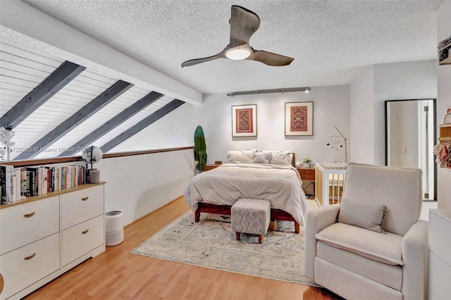 bedroom with a textured ceiling, ceiling fan, lofted ceiling with beams, and light hardwood / wood-style floors