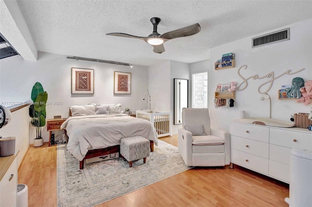 bedroom featuring a textured ceiling, ceiling fan, and light hardwood / wood-style floors