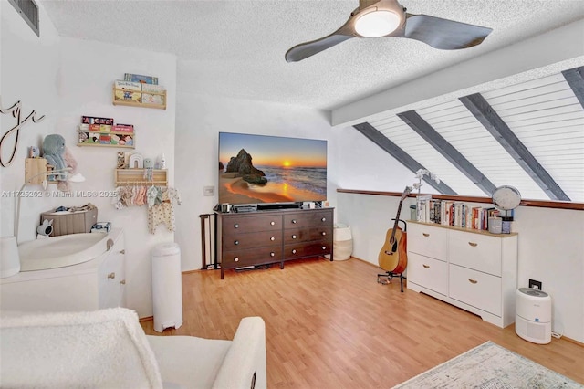 bedroom featuring a textured ceiling, ceiling fan, light hardwood / wood-style flooring, and lofted ceiling with beams