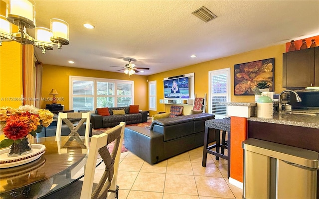 living room featuring sink, a textured ceiling, ceiling fan, and light tile patterned floors