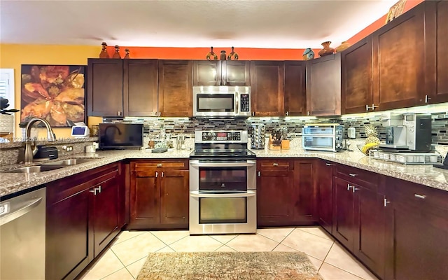 kitchen featuring light stone counters, appliances with stainless steel finishes, tasteful backsplash, and sink