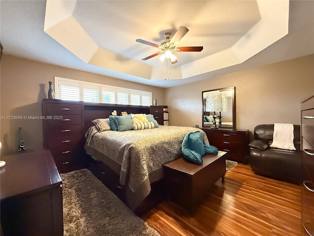 bedroom featuring hardwood / wood-style flooring, ceiling fan, and a tray ceiling