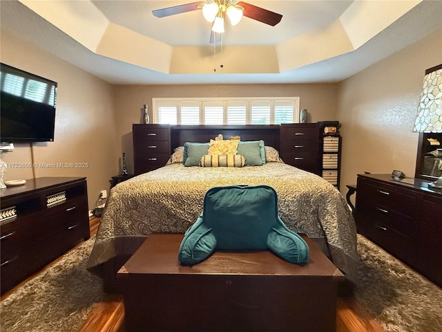 bedroom featuring hardwood / wood-style floors, ceiling fan, and a tray ceiling