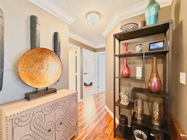 hallway with a textured ceiling, light wood-type flooring, and crown molding