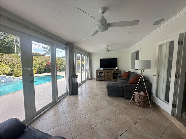 living room with crown molding, ceiling fan, light tile patterned floors, and a healthy amount of sunlight