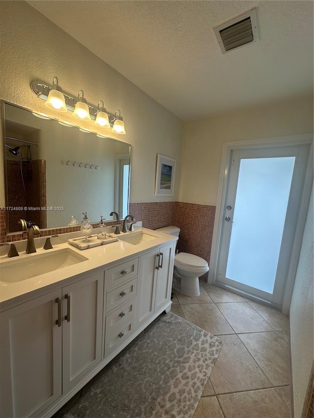 bathroom featuring a textured ceiling, tile patterned flooring, vanity, and toilet