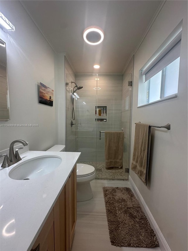 bathroom with walk in shower, crown molding, vanity, and toilet