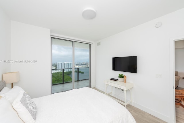 bedroom featuring floor to ceiling windows, light hardwood / wood-style floors, and access to outside