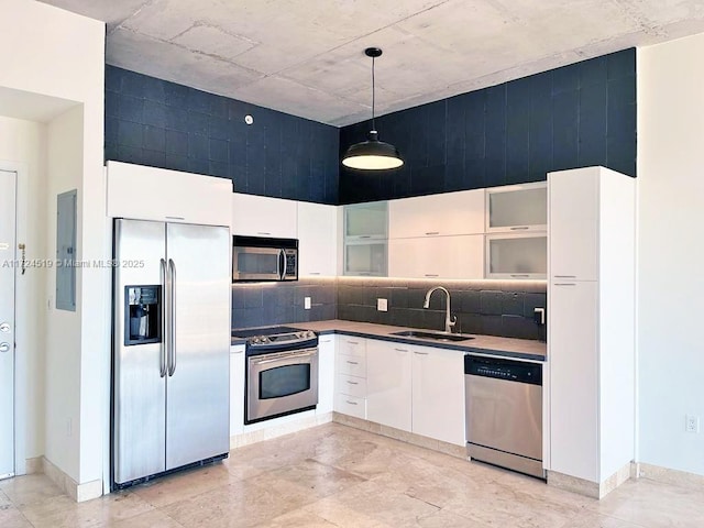 kitchen with hanging light fixtures, backsplash, white cabinets, appliances with stainless steel finishes, and sink