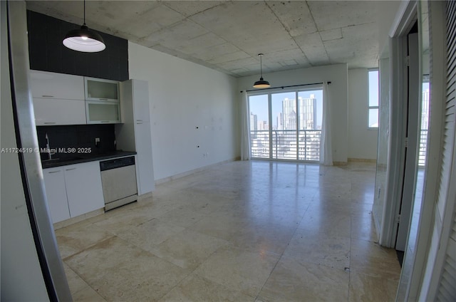 kitchen with dark countertops, hanging light fixtures, a city view, white cabinetry, and stainless steel dishwasher