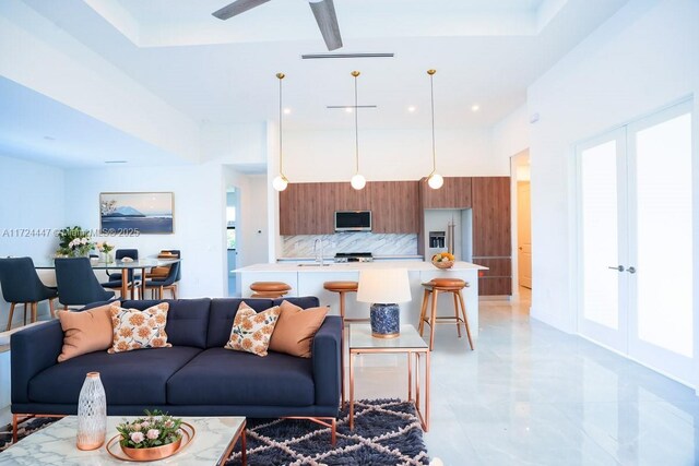 living room featuring ceiling fan, sink, and plenty of natural light