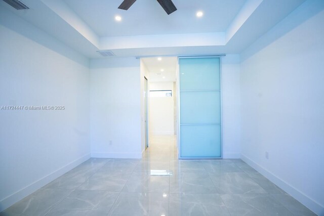 unfurnished room featuring a raised ceiling and ceiling fan