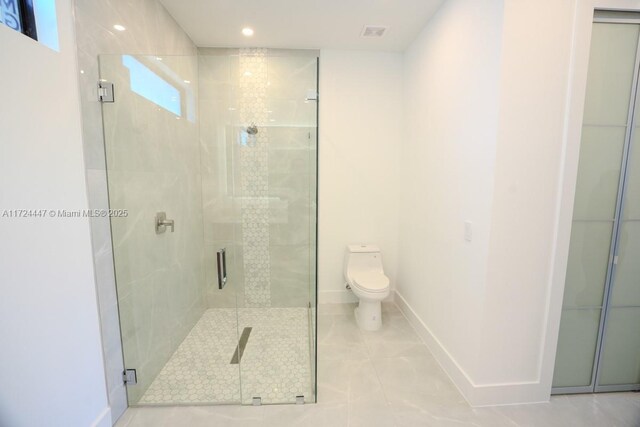 bathroom featuring toilet, an enclosed shower, and plenty of natural light