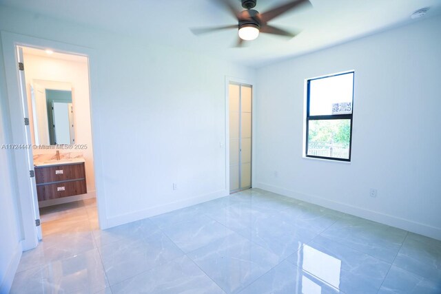 unfurnished bedroom featuring ceiling fan, ensuite bathroom, and sink