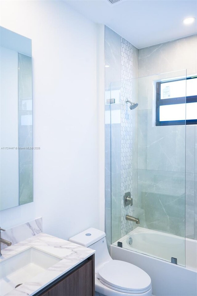 full bathroom featuring vanity, tiled shower / bath combo, and toilet