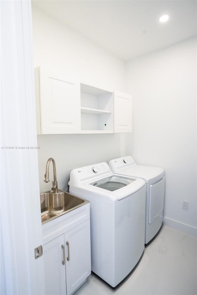 washroom featuring washer and dryer, sink, and cabinets