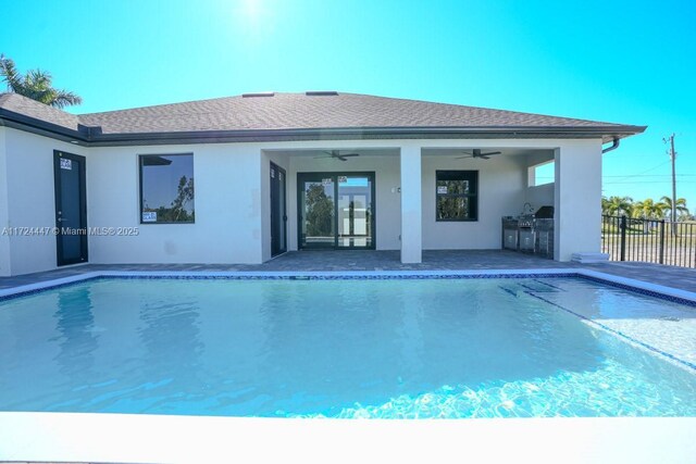 view of swimming pool featuring an outdoor kitchen, ceiling fan, and a patio area