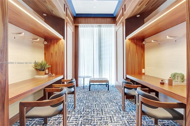 interior space featuring built in desk, carpet floors, and wooden walls