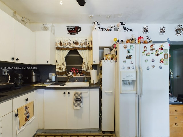 kitchen with white fridge with ice dispenser, white cabinets, backsplash, and sink