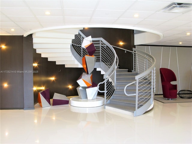 stairs featuring a paneled ceiling and tile patterned floors