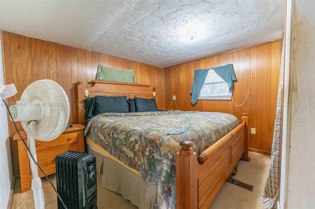 bedroom with light colored carpet, wooden walls, and a textured ceiling