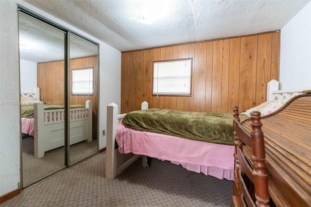 bedroom with a closet, carpet flooring, a textured ceiling, and wood walls