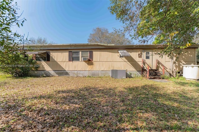 back of property with cooling unit, central AC, and a lawn