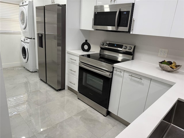 kitchen with stacked washer and dryer, appliances with stainless steel finishes, and white cabinetry