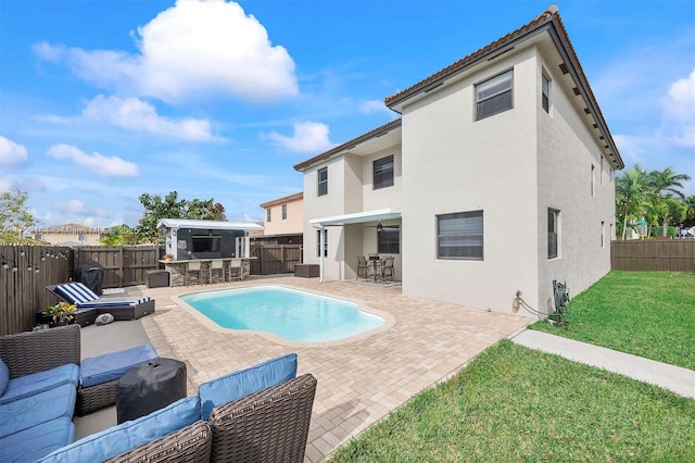 view of pool featuring an outdoor hangout area, a patio, a yard, an outdoor kitchen, and an outdoor bar