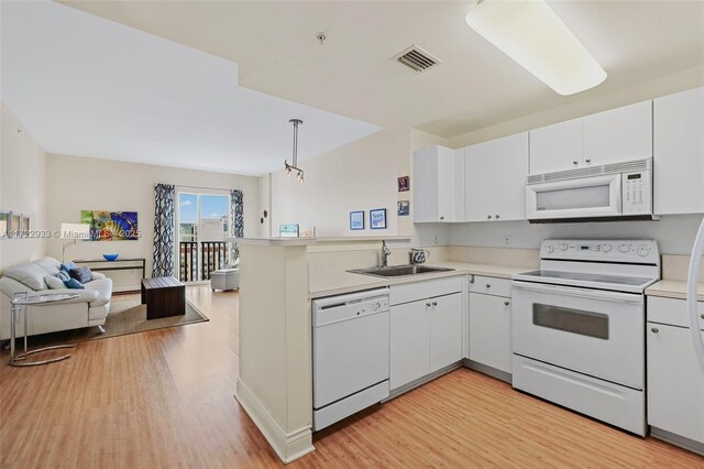 kitchen featuring white appliances, kitchen peninsula, pendant lighting, white cabinets, and sink