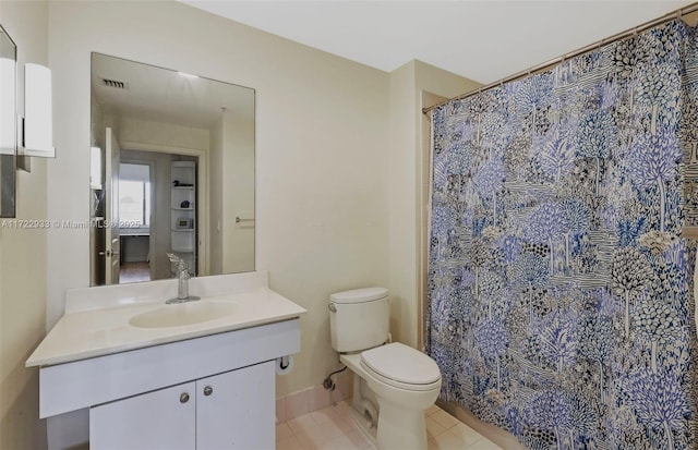 bathroom with tile patterned flooring, vanity, walk in shower, and toilet