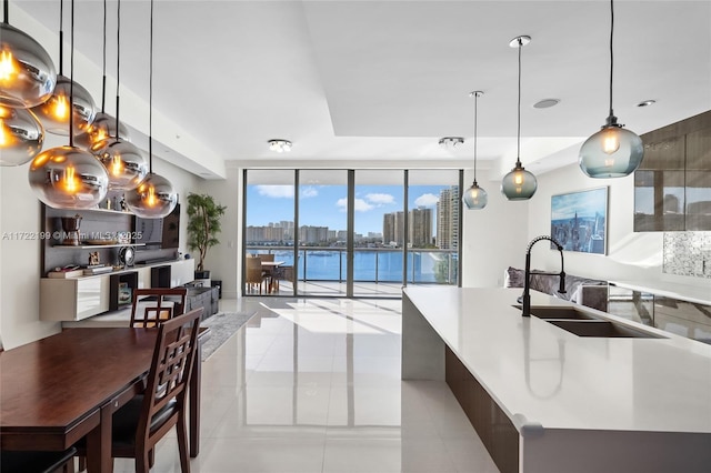 kitchen featuring sink, decorative light fixtures, a water view, expansive windows, and a kitchen island with sink