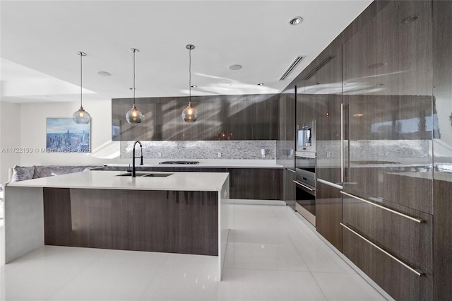 kitchen with hanging light fixtures, light tile patterned floors, decorative backsplash, a spacious island, and sink